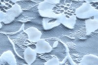 Delicate white lace fabric with floral pattern and butterfly motifs creates romantic texture, seamless background for wedding designs and feminine projects.