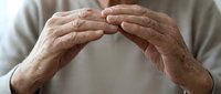 Elderly hands forming protective shelter gesture, senior care and security concept for healthcare and insurance materials.