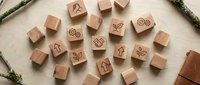 Wooden rubber stamps with nature symbols scattered on textured paper surface. Eco-friendly craft supplies for scrapbooking and DIY projects.