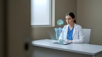 Female doctor in white coat sitting at desk with holographic brain scan display in modern medical office for healthcare technology presentations.