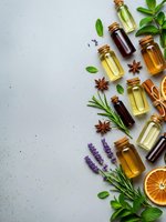 Essential oils in glass bottles with fresh herbs, spices and citrus on gray background. Natural aromatherapy and wellness concept with copy space.