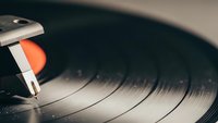 Vintage turntable stylus needle on spinning vinyl record with warm lighting creating nostalgic music atmosphere for audio entertainment and retro sound.
