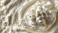 Creamy white whipped cream swirl with soft peaks and powdery texture, macro photography showing rich dairy dessert topping detail and airy consistency.