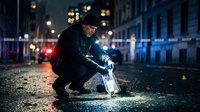 Crime scene investigator collecting evidence with flashlight on urban street at night for forensic analysis and police investigation work.