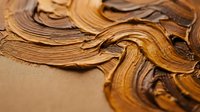 Thick brown oil paint brushstrokes creating textured swirls and curves on canvas surface for artistic backgrounds and creative projects.