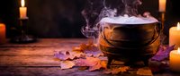 Mystical cauldron with bubbling potion surrounded by flickering candles and autumn leaves on rustic wooden surface creating magical Halloween atmosphere.