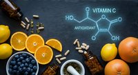Vitamin C rich foods with molecular structure diagram. Fresh citrus fruits, blueberries and supplements on dark background for healthy nutrition concepts.