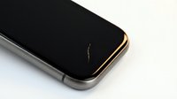 Cracked smartphone screen with damaged black display showing yellow lightning-shaped fracture on modern mobile device against white background.
