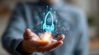 Glowing blue rocket hologram floating above businessman's palm with magical light effect and particles, representing startup business innovation.