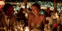 Elegant couple enjoying romantic dinner date at upscale restaurant with candlelight and city lights creating intimate atmosphere for special evening celebration.