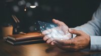 Business professional holding holographic digital network interface with glowing connections and data points above hands in modern office workspace.