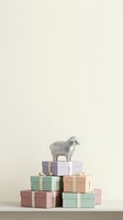 Stacked gift boxes in pastel colors with white ribbons and a silver goat figurine on top against neutral background, suitable for holiday, celebration, and retail marketing materials.