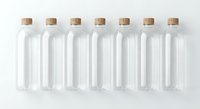 Seven empty glass bottles with cork stoppers arranged in row on white background for packaging design and branding projects.