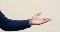 Male hand extended in open gesture wearing navy blue sweater sleeve against neutral background for presentation concepts.