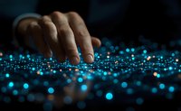 Fingers touching glowing blue particles scattered on dark surface creating magical atmosphere. Abstract technology concept with bokeh light effects.
