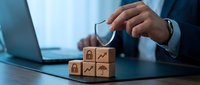 Professional businessman protecting wooden blocks with security and growth icons using umbrella gesture for risk management and business protection strategy.