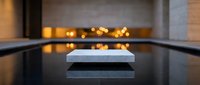 Elegant white marble podium on reflective dark surface with warm bokeh lights, luxury product display stand for cosmetics or jewelry showcase.