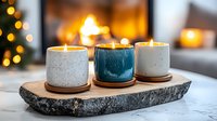 Cozy ceramic candles on rustic stone tray with warm fireplace glow and bokeh lights in background create relaxing hygge atmosphere for home decor and wellness.
