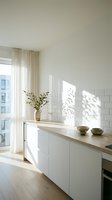 Bright minimalist kitchen with white subway tile backsplash, wooden countertop, and natural light streaming through sheer curtains, featuring modern cabinetry and decorative bowls.
