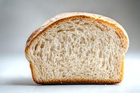 Fresh sliced white bread showing detailed inner texture and golden crust against light background, highlighting soft airy crumb structure and artisanal quality.