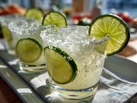 Refreshing lime cocktails with salt rim and ice cubes served on tray, perfect for summer parties and celebrations.