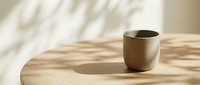 Ceramic cup on wooden table with natural sunlight casting shadows, minimalist home decor and tableware styling.