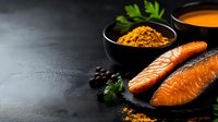 Fresh salmon fillets with turmeric spice and herbs on dark slate background for healthy cooking and culinary preparation concepts.
