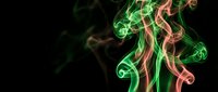 Colorful smoke swirls in green and pink hues creating abstract flowing patterns against black background for creative design projects and artistic compositions.