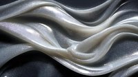Abstract flowing silver metallic waves with smooth curves and glossy surface creating elegant dynamic movement against dark background.