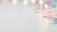 Soft blurred colorful lights and confetti on white surface creating dreamy party atmosphere with copy space for text and design elements.