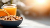 Breakfast cereal in dark bowl with fresh orange slice and glass of juice on blurred background, morning meal and healthy eating concept.