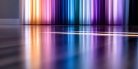 Vibrant multicolored light beams reflecting on glossy surface creating dramatic mirror effect with orange, blue and purple neon glow in dark background.