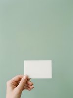 Hand holding blank white business card against soft sage green background, ready for branding and corporate identity design projects.