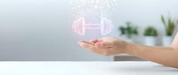 Hand holding glowing pink dumbbell icon above white surface, symbolizing fitness goals, workout planning, and health technology for gym and wellness applications.