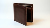Brown leather bifold wallet open slightly, showing cards inside, isolated on white background. Classic men's accessory for finance and style.