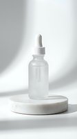 Clear glass dropper bottle with white cap displayed on a marble podium against neutral background, suitable for cosmetics, serums, essential oils, and skincare product packaging design.