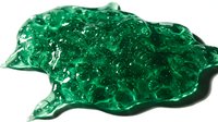 Vibrant emerald green crushed glass or crystal fragments with reflective sparkle and translucent quality, suitable for decorative, craft, and design projects.
