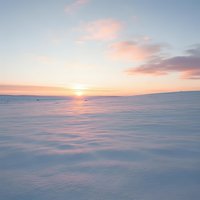 Serene ocean sunset with pastel pink and purple clouds reflecting on calm water surface creating peaceful seascape for meditation and wellness content.