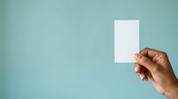Hand holding blank white card against turquoise background for mockup, branding, and business card presentation purposes.