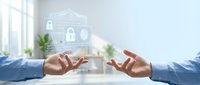 Home security protection concept with two hands in blue shirts holding digital lock and shield icons above, representing safe property and data protection for real estate and insurance industries.