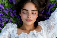 Young woman with closed eyes in white lace dress surrounded by purple flowers in peaceful natural beauty portrait for wellness and relaxation concepts.