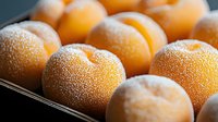 Fresh ripe mandarin oranges covered in morning frost or condensation droplets on dark surface, macro food photography showing detailed citrus texture.