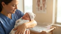 Caucasian mother in blue hospital gown tenderly holding newborn baby in maternity ward. Peaceful bonding moment between parent and infant after delivery.