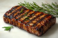Juicy grilled steak with charred grill marks and fresh rosemary garnish on light background. Close up view of perfectly cooked meat showing caramelized surface.