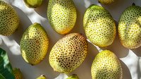 Fresh spotted yellow and brown pears arranged on white textured background with natural shadows and soft lighting, top view composition for food photography.