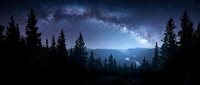 Stunning night sky panorama with Milky Way galaxy over mountain forest landscape. Starry celestial view through silhouetted pine trees creates magical atmosphere.
