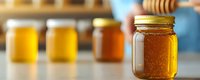 Fresh raw honey in glass mason jars arranged on wooden surface with golden warm lighting, selective focus on front jar showing natural crystallization pattern.