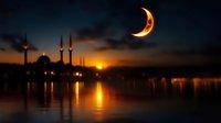 Crescent moon over silhouette of mosque with minarets at sunset, golden light reflecting on calm water surface against dark blue sky.