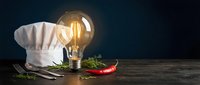 Chef hat with glowing light bulb and red chili pepper on wooden table representing culinary creativity and cooking inspiration for restaurant menu design.