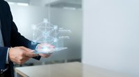 Businessman holding tablet displaying holographic network connections and data visualization in modern office environment for digital transformation concepts.